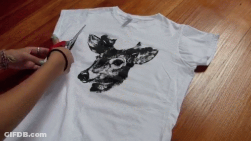 A Person Is Cutting A White T-Shirt With A Deer On It GIF