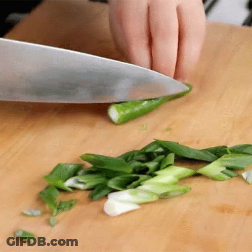 A Person Is Cutting Green Onions With A Knife On A Cutting Board GIF