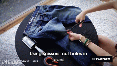 A Person Is Cutting Holes In A Pair Of Jeans GIF