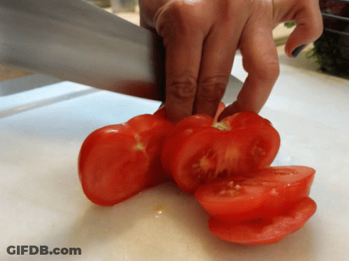 A Person Is Cutting Tomatoes On A White Cutting Board GIF