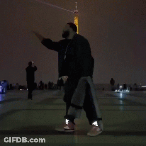 A Person Is Dancing In Front Of The Eiffel Tower At Night GIF