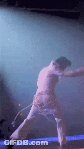 A Person Is Dancing On A Stage With A Purple Background GIF