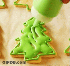 A Person Is Decorating A Cookie In The Shape Of A Christmas Tree GIF