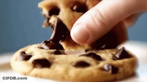 A Person Is Dipping A Chocolate Chip Cookie In Chocolate Sauce GIF