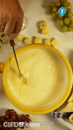 A Person Is Dipping A Piece Of Cheese Into A Bowl Of Fondue GIF