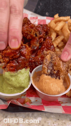 A Person Is Dipping A Piece Of Fried Chicken Into Guacamole Sauce GIF