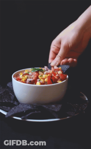 A Person Is Dipping A Tortilla Chip Into A Bowl Of Salsa GIF