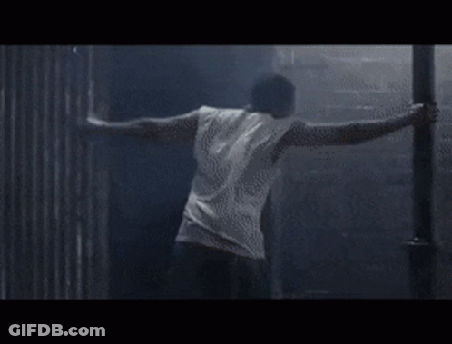 A Person Is Doing A Handstand In A Dark Room . GIF