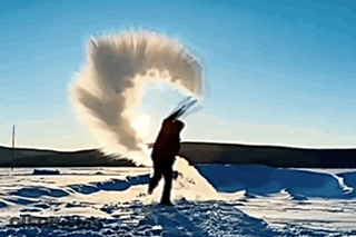 A Person Is Doing A Handstand In The Snow In Front Of A Large Explosion Of Snow GIF