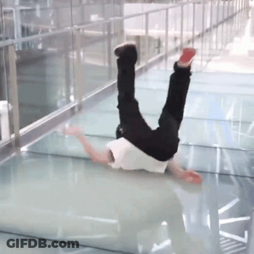 A Person Is Doing A Handstand On A Glass Walkway GIF