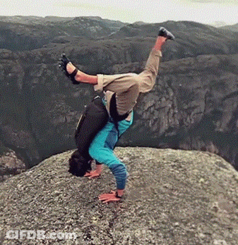 A Person Is Doing A Handstand On A Rocky Cliff . GIF