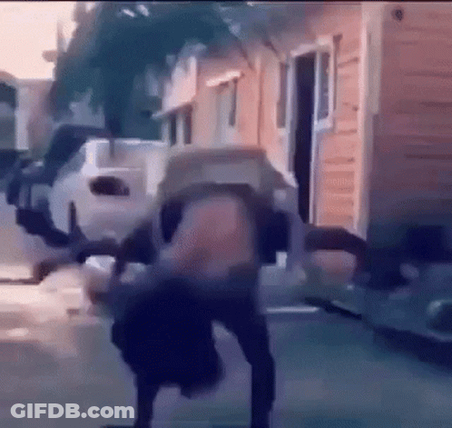 A Person Is Doing A Handstand On A Sidewalk In Front Of A Building . GIF