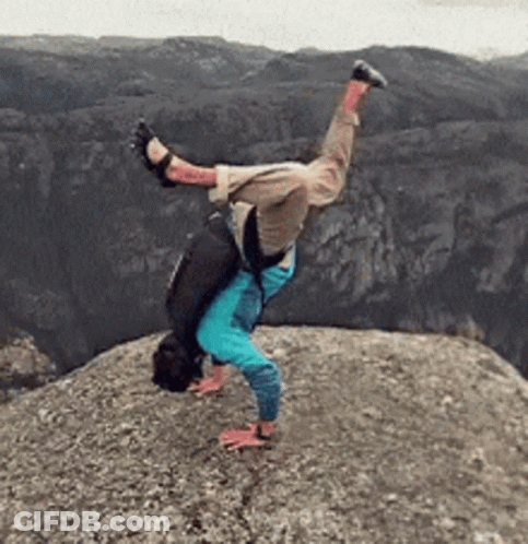 A Person Is Doing A Handstand On Top Of A Rocky Cliff GIF