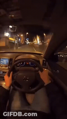 A Person Is Driving A Car At Night And Their Hands Are On The Steering Wheel And The Dashboard GIF