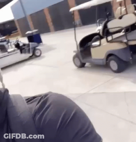 A Person Is Driving A Golf Cart In A Parking Lot GIF