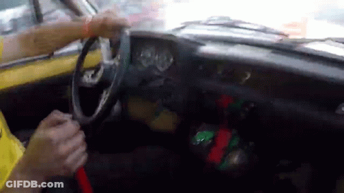 A Person Is Driving A Yellow Car And Holding The Steering Wheel GIF