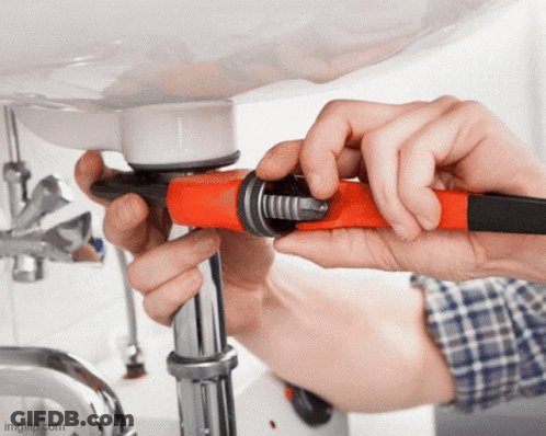 A Person Is Fixing A Pipe Under A Sink Using A Wrench GIF