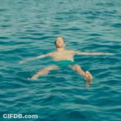 A Person Is Floating On Their Stomach In The Ocean . GIF