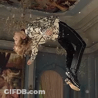 A Person Is Flying Through The Air In A Room With A Painting On The Wall . GIF