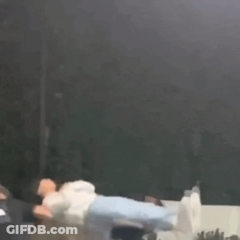 A Person Is Flying Through The Air While A Group Of People Watch . GIF
