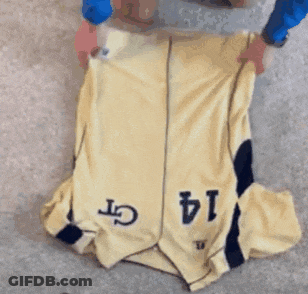 A Person Is Folding A Yellow Jersey With The Number 14 On It GIF