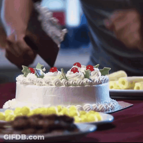 A Person Is Frosting A Cake With Whipped Cream And Cherry Decorations GIF