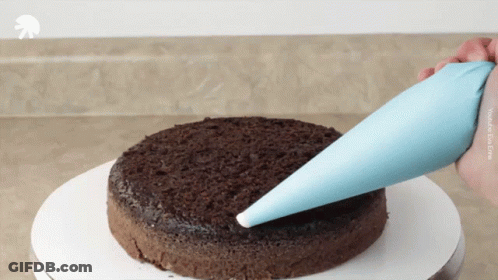 A Person Is Frosting A Chocolate Cake With A Blue Bag That Says Youtube On The Bottom GIF