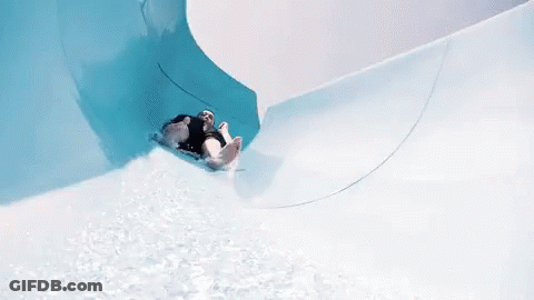 A Person Is Going Down A Water Slide In A Pool GIF