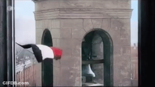 A Person Is Hanging From A Tower With A Flag On It GIF