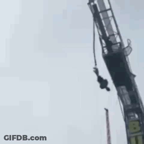 A Person Is Hanging Upside Down From A Bungee Tower . GIF