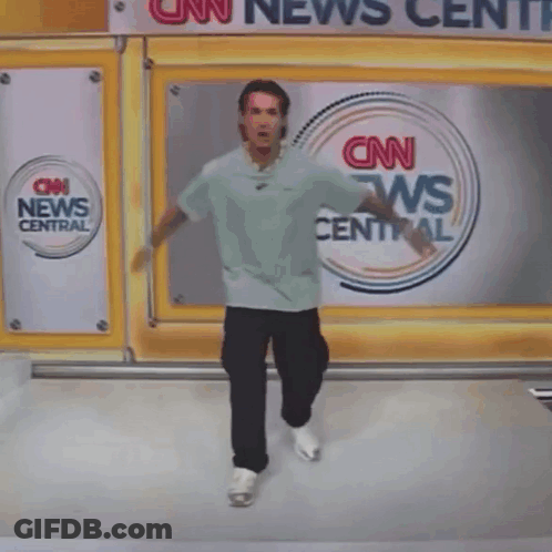 A Person Is Hanging Upside Down In Front Of A Cnn News Center Sign GIF