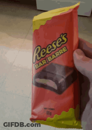 A Person Is Holding A Bag Of Reese 'S Bar GIF