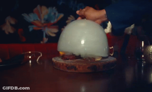 A Person Is Holding A Balloon With Smoke Coming Out Of It On A Table GIF