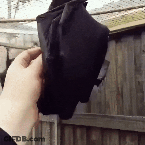 A Person Is Holding A Bat Hanging From A Fence GIF