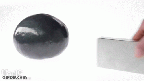 A Person Is Holding A Block Next To A Black Ball And A Vat19.com Logo GIF
