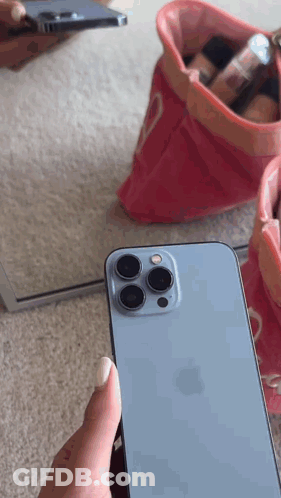 A Person Is Holding A Blue Iphone In Front Of A Mirror GIF