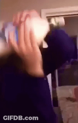 A Person Is Holding A Bottle In Their Hand In A Room . GIF