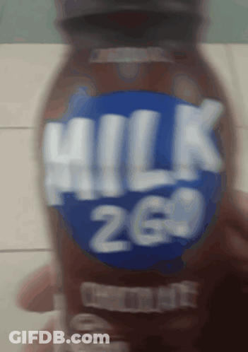 A Person Is Holding A Bottle Of Milk That Has The Number 26 On It GIF