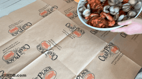 A Person Is Holding A Bowl Of Crawfish On A Crab Place Bag GIF