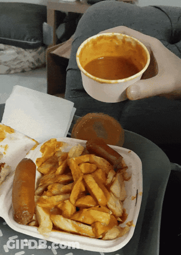 A Person Is Holding A Bowl Of Sauce Over A Plate Of Food GIF