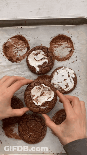 A Person Is Holding A Brownie With Marshmallow Frosting On It GIF
