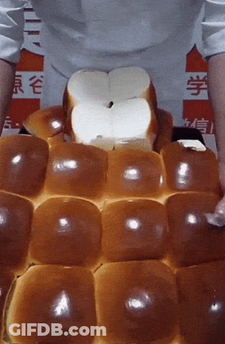 A Person Is Holding A Bunch Of Bread In Front Of A Sign That Says ' Chinese ' On It GIF