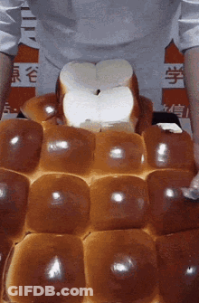 A Person Is Holding A Bunch Of Bread In Front Of A Sign That Says ' Chinese ' On It GIF