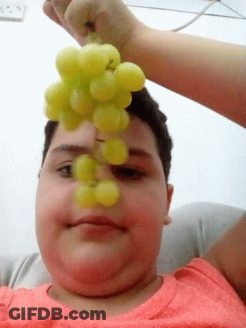 A Person Is Holding A Bunch Of Grapes To Their Face GIF