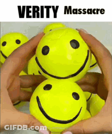 A Person Is Holding A Bunch Of Yellow Smiley Faces In Their Hands .. GIF