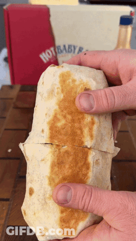 A Person Is Holding A Burrito In Front Of A Hot Baby Box GIF