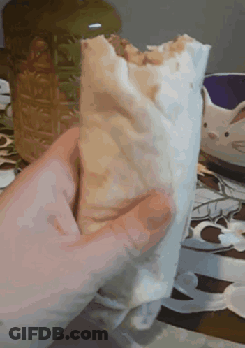 A Person Is Holding A Burrito In Their Hand GIF