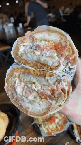 A Person Is Holding A Burrito That Has A Lot Of Toppings GIF