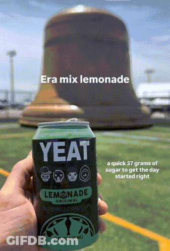 A Person Is Holding A Can Of Yeat Lemonade In Front Of A Large Bell GIF