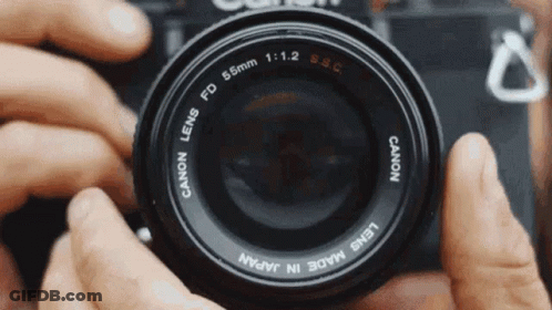 A Person Is Holding A Canon Camera Lens In Their Hands GIF